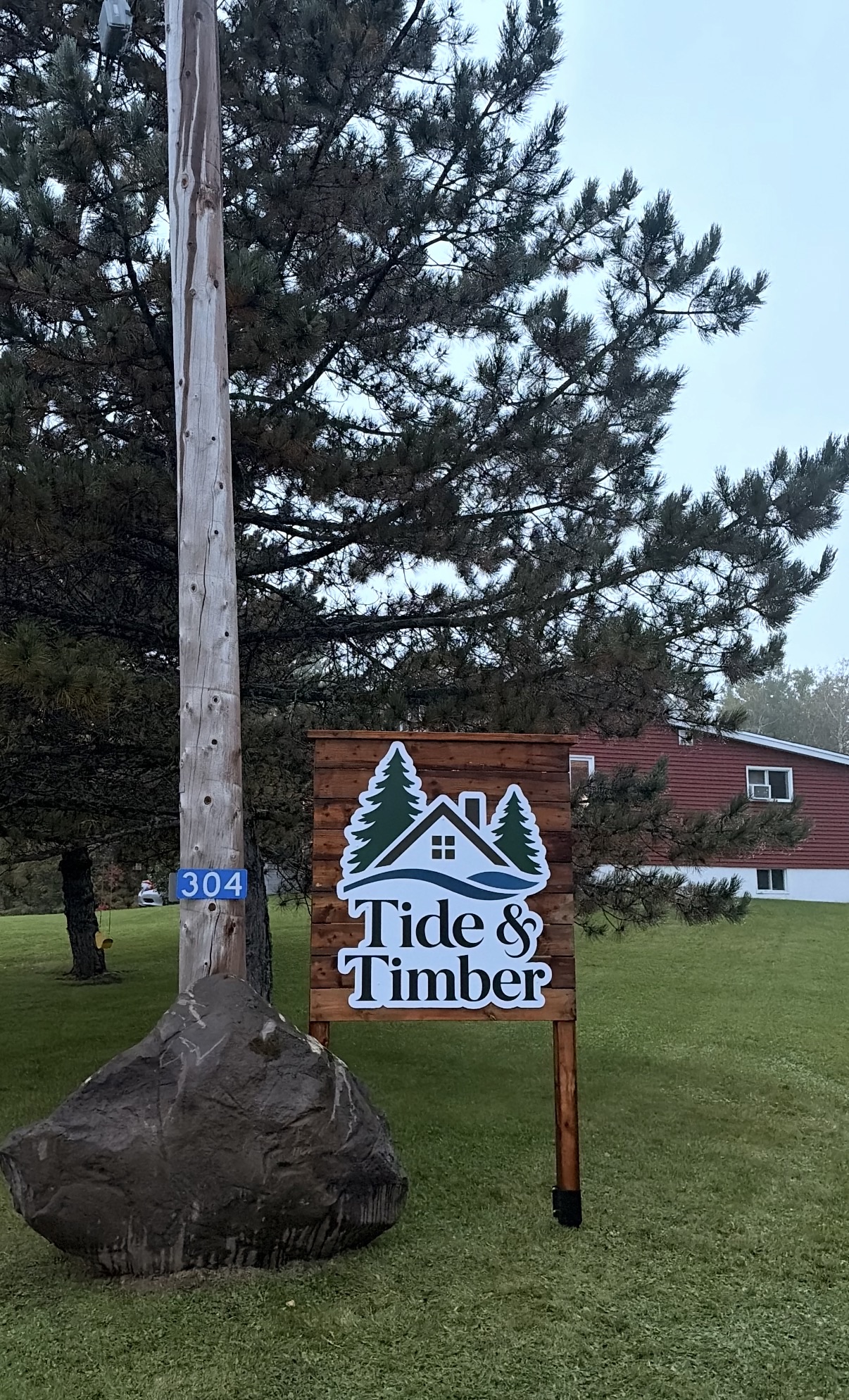 Custom Tide and Timber outdoor business sign mounted on a wood backdrop